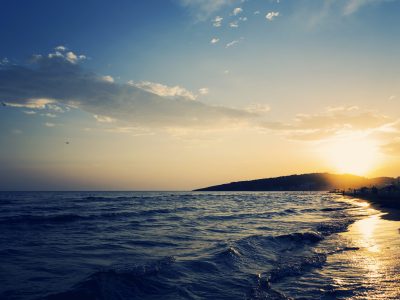 A beautiful shot of the sandy shoreline of the sea with an amazing sunset in the background